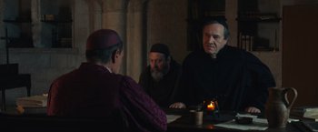 Movie still from “Benedetta” (2021), directed by Paul Verhoeven – A group of men sitting at a table in front of a candle; Medium shot, Over the shoulder angle