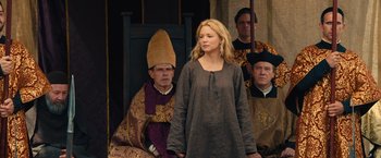 Movie still from “Benedetta” (2021), directed by Paul Verhoeven – A woman standing in front of a group of people; Medium shot, Over the shoulder angle