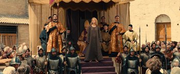 Movie still from “Benedetta” (2021), directed by Paul Verhoeven – A woman standing on top of steps in front of a group of men; Wide shot, Low angle