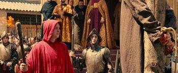 Movie still from “Benedetta” (2021), directed by Paul Verhoeven – Two people dressed in medieval costumes and one is wearing a red hood; Medium shot, Over the shoulder angle