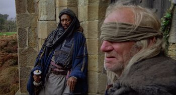 Movie still from “Robin Hood: Prince of Thieves” (1991), directed by Kevin Reynolds – A man with a blindfold and a man with a beard; Medium shot, Over the shoulder angle