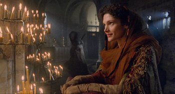 Movie still from “Robin Hood: Prince of Thieves” (1991), directed by Kevin Reynolds – A woman sitting on a chair in a room with candles; Medium shot, Over the shoulder angle