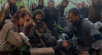 Movie still from “Robin Hood: Prince of Thieves” (1991), directed by Kevin Reynolds – A group of people in the woods with a trunk; Medium shot, Over the shoulder angle