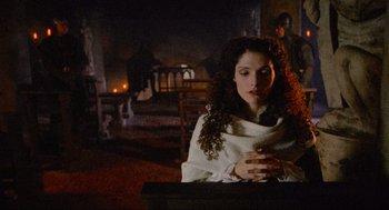 Movie still from “Robin Hood: Prince of Thieves” (1991), directed by Kevin Reynolds – A woman sitting in front of a fireplace with her eyes closed; Medium shot, Over the shoulder angle