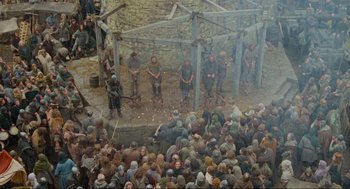 Movie still from “Robin Hood: Prince of Thieves” (1991), directed by Kevin Reynolds – A group of men standing next to each other in front of a crowd of onlookers; Extreme Wide shot, High angle