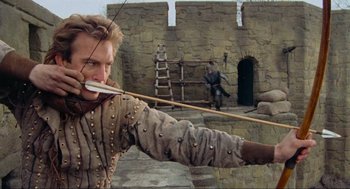Movie still from “Robin Hood: Prince of Thieves” (1991), directed by Kevin Reynolds – A man in medieval garb holding a bow and arrow; Medium shot, Low angle