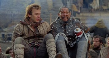 Movie still from “Robin Hood: Prince of Thieves” (1991), directed by Kevin Reynolds – Two men sitting next to each other on the ground; Medium shot, Low angle