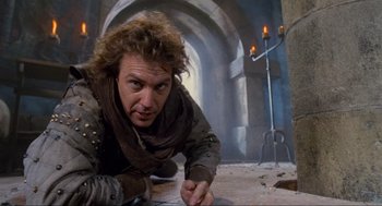 Movie still from “Robin Hood: Prince of Thieves” (1991), directed by Kevin Reynolds – A man laying on the ground writing on a piece of paper; Close Up shot, Low angle