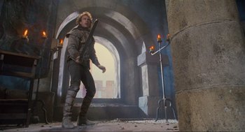 Movie still from “Robin Hood: Prince of Thieves” (1991), directed by Kevin Reynolds – A man holding a sword standing in front of an archway; Wide shot, Low angle