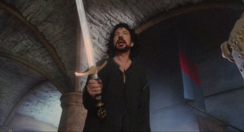 Movie still from “Robin Hood: Prince of Thieves” (1991), directed by Kevin Reynolds – A man holding a sword in his hand; Medium shot, Low angle