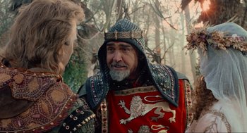 Movie still from “Robin Hood: Prince of Thieves” (1991), directed by Kevin Reynolds – A man wearing a red and black outfit and a crown; Close Up shot, Over the shoulder angle