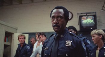 Movie still from “RoboCop” (1987), directed by Paul Verhoeven – A man in a police uniform standing in front of a group of people; Close Up shot, Low angle