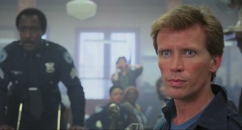 Movie still from “RoboCop” (1987), directed by Paul Verhoeven – A person in a room with other people; Close Up shot, Over the shoulder angle