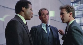 Movie still from “RoboCop” (1987), directed by Paul Verhoeven – A group of men in suits and ties standing next to each other; Medium shot, Low angle