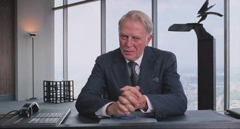 Movie still from “RoboCop” (1987), directed by Paul Verhoeven – An older man sitting at a table in front of a window; Medium shot, Over the shoulder angle