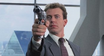 Movie still from “RoboCop” (1987), directed by Paul Verhoeven – A man in a suit and tie holding a gun in his hand; Close Up shot, Low angle