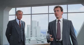 Movie still from “RoboCop” (1987), directed by Paul Verhoeven – Two businessmen standing in front of a large window in an office building; Medium shot, Low angle