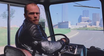 Movie still from “RoboCop” (1987), directed by Paul Verhoeven – A man in a black leather jacket driving a truck; Medium shot, Over the shoulder angle