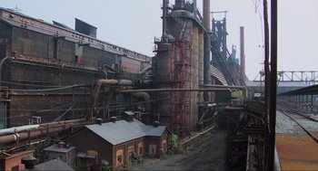 Movie still from “RoboCop” (1987), directed by Paul Verhoeven – An industrial area with many buildings and pipes; Extreme Wide shot, High angle