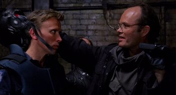 Movie still from “RoboCop” (1987), directed by Paul Verhoeven – A man with glasses is getting his face painted by another man; Close Up shot, Over the shoulder angle