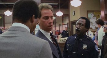 Movie still from “RoboCop” (1987), directed by Paul Verhoeven – A group of men standing next to each other in a room; Medium shot, Over the shoulder angle