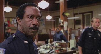 Movie still from “RoboCop” (1987), directed by Paul Verhoeven – A man standing in front of another man in a cluttered room; Close Up shot, Low angle