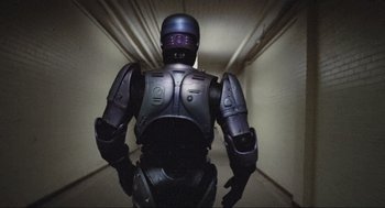 Movie still from “RoboCop” (1987), directed by Paul Verhoeven – The back end of a robot in a hallway; Wide shot, Low angle