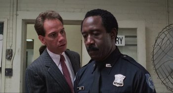 Movie still from “RoboCop” (1987), directed by Paul Verhoeven – Two men standing next to each other in front of a building; Close Up shot, Low angle