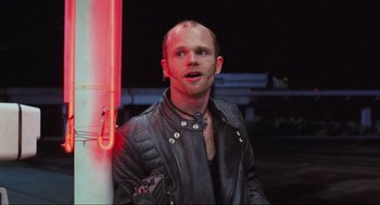Movie still from “RoboCop” (1987), directed by Paul Verhoeven – A man wearing a leather jacket standing next to a pole; Close Up shot, Over the shoulder angle