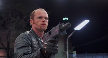 Movie still from “RoboCop” (1987), directed by Paul Verhoeven – A man in a leather jacket holding a gun; Close Up shot, Low angle