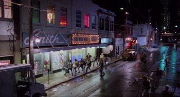 Movie still from “RoboCop” (1987), directed by Paul Verhoeven – A group of people walking down a street at night; Extreme Wide shot, High angle
