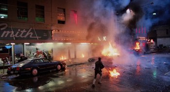 Movie still from “RoboCop” (1987), directed by Paul Verhoeven – A man running in front of a burning car; Extreme Wide shot, High angle