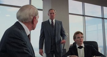 Movie still from “RoboCop” (1987), directed by Paul Verhoeven – A man in a suit and tie standing in front of two other men; Medium shot, Over the shoulder angle