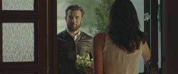 Movie still from “Robots” (2023), directed by Casper Christensen – A man standing in front of a mirror holding a bouquet; Medium shot, Over the shoulder angle