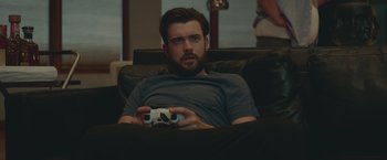 Movie still from “Robots” (2023), directed by Casper Christensen – A man sitting on top of a couch holding a game controller; Close Up shot, High angle