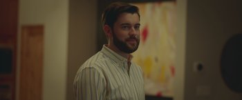 Movie still from “Robots” (2023), directed by Casper Christensen – A man in a striped shirt is smiling for the camera; Close Up shot, Over the shoulder angle