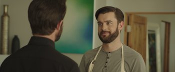 Movie still from “Robots” (2023), directed by Casper Christensen – A man with a beard is talking to another man in front of a painting; Close Up shot, Over the shoulder angle
