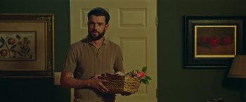 Movie still from “Robots” (2023), directed by Casper Christensen – A man holding two baskets with flowers in them; Medium shot, Over the shoulder angle