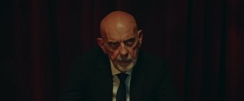 Movie still from “Robots” (2023), directed by Casper Christensen – An older man wearing a suit and tie; Medium shot, Low angle