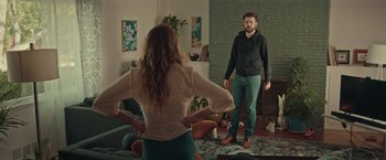 Movie still from “Robots” (2023), directed by Casper Christensen – A man and a woman standing in a living room; Medium shot, Over the shoulder angle
