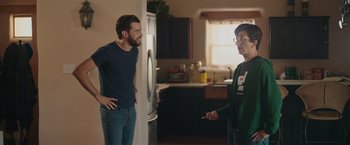 Movie still from “Robots” (2023), directed by Casper Christensen – Two men in a kitchen one of which is holding a remote control; Medium shot, Over the shoulder angle