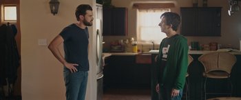 Movie still from “Robots” (2023), directed by Casper Christensen – Two men standing in a kitchen talking to each other; Medium shot, Over the shoulder angle