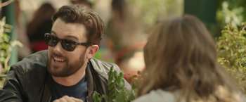 Movie still from “Robots” (2023), directed by Casper Christensen – A person wearing sunglasses and a leather jacket; Close Up shot, Over the shoulder angle