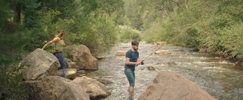 Movie still from “Robots” (2023), directed by Casper Christensen – A man in a river holding a fishing rod; Wide shot, High angle