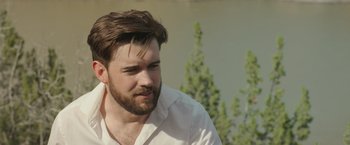 Movie still from “Robots” (2023), directed by Casper Christensen – A man with a beard is looking to his left; Close Up shot, Over the shoulder angle
