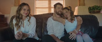 Movie still from “Robots” (2023), directed by Casper Christensen – A man and a woman sitting next to each other on a couch; Medium shot, Over the shoulder angle