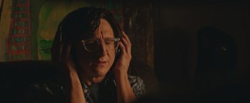 Movie still from “Robots” (2023), directed by Casper Christensen – A man with glasses is listening to music on his headphones; Close Up shot, Over the shoulder angle