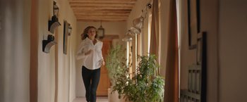 Movie still from “Robots” (2023), directed by Casper Christensen – A woman in a white shirt is running in a hallway; Wide shot, Low angle