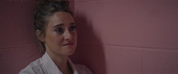 Movie still from “Robots” (2023), directed by Casper Christensen – A woman in a white shirt is standing against a pink wall; Close Up shot, Over the shoulder angle
