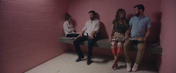 Movie still from “Robots” (2023), directed by Casper Christensen – A man and two women sitting on a bench in a room; Wide shot, Over the shoulder angle
